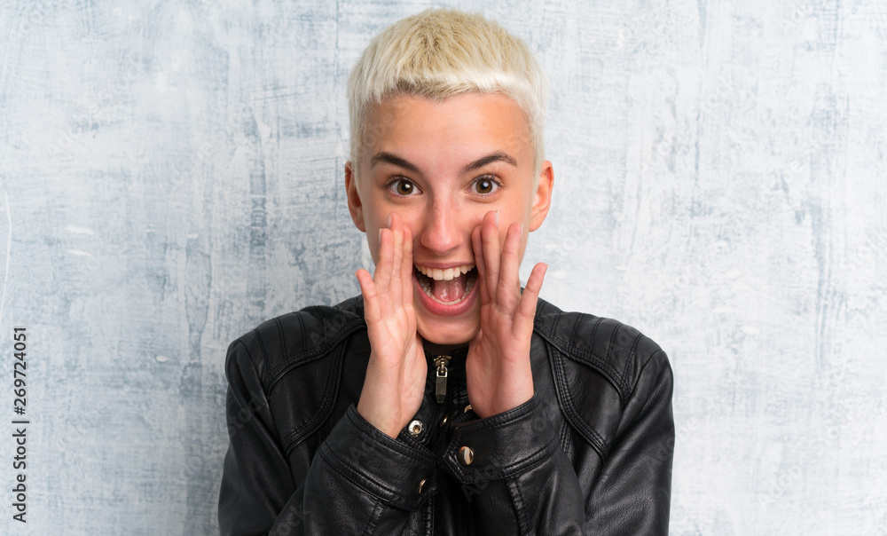 Young woman over grunge wall shouting with mouth wide open Young woman over grunge wall shouting with mouth wide open