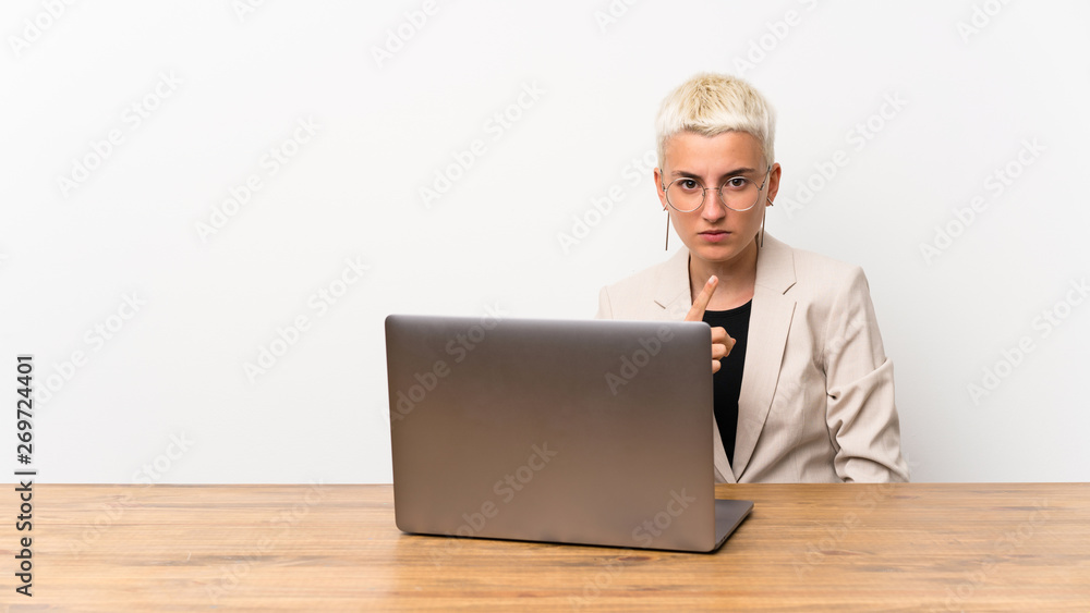Teenager girl with short hair with a laptop frustrated and pointing to the front Teenager girl with short hair with a laptop frustrated and pointing to the front