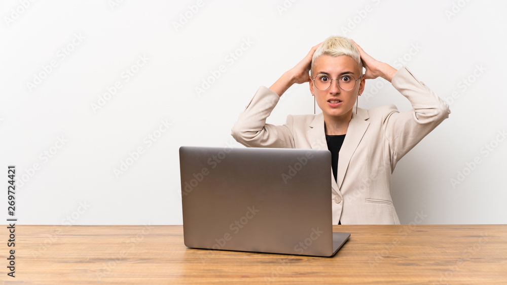 Teenager girl with short hair with a laptop frustrated and takes hands on head Teenager girl with short hair with a laptop frustrated and takes hands on head