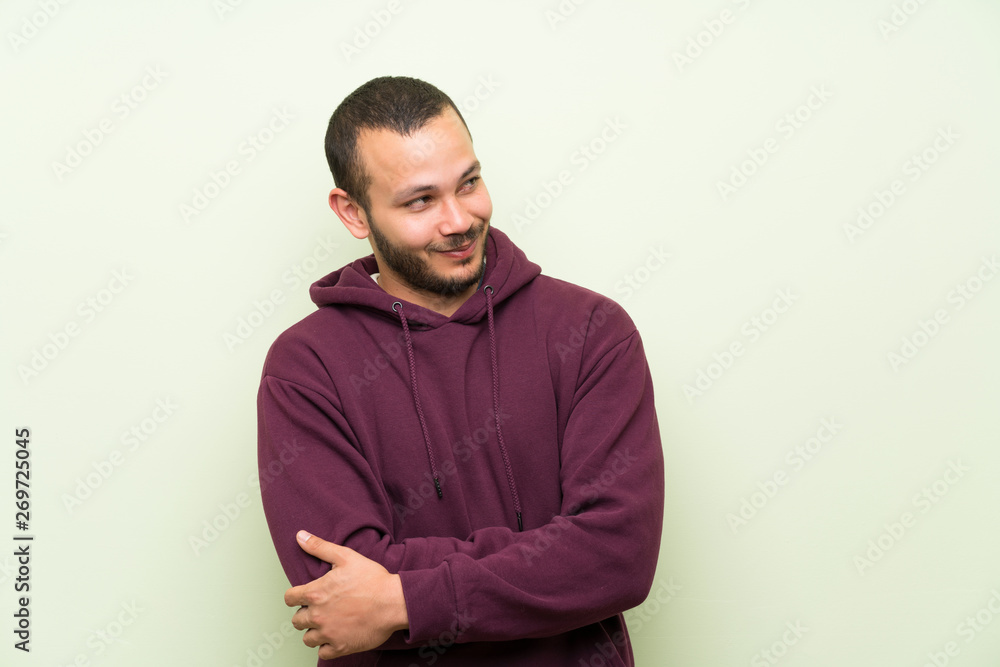 Fototapeta premium Colombian man with sweatshirt over green wall thinking an idea