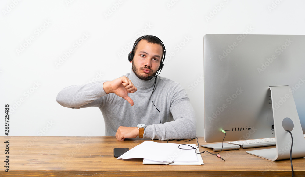Telemarketer Colombian man showing thumb down with negative expression Telemarketer Colombian man showing thumb down with negative expression
