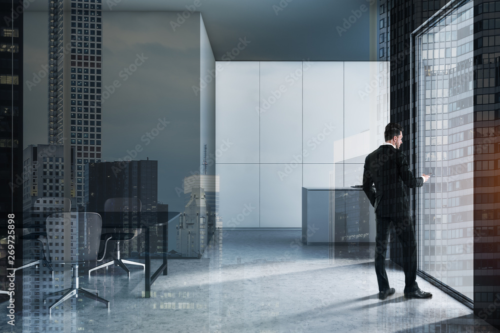 Fototapeta premium Man with phone in gray kitchen with table
