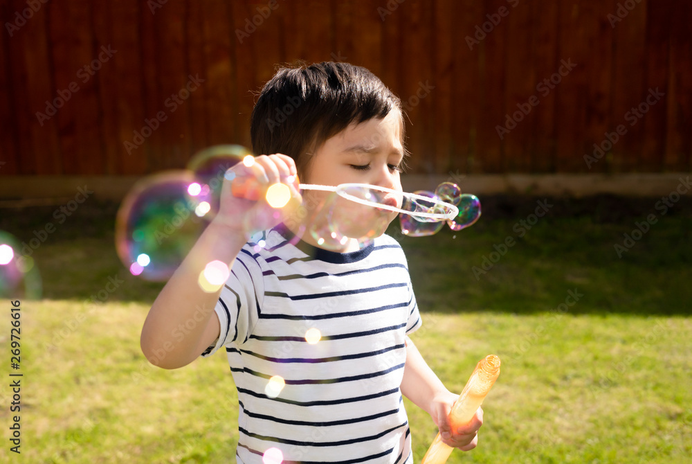 Happy boy blowing soap bubbles in the garden,Cute 4 years old kid blowing bubble wand with a funny face,Cute kid playing in the garden on a sunny summer day,Outdoor activities for Children Happy boy blowing soap bubbles in the garden,Cute 4 years old kid blowing bubble wand with a funny face,Cute kid playing in the garden on a sunny summer day,Outdoor activities for Children