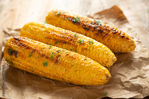 Grilled corn cobs on wood background.