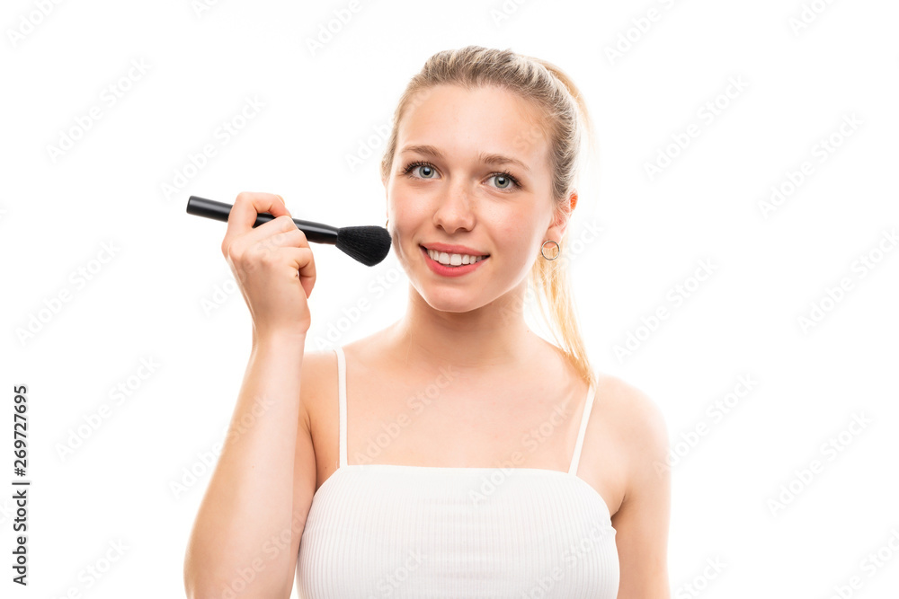 Young blonde woman over isolated white background with makeup brush Young blonde woman over isolated white background with makeup brush