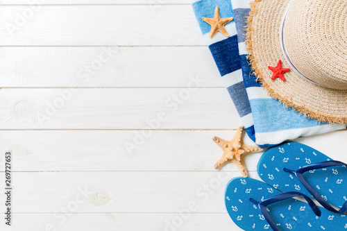 Straw hat, blue flip flops, towel and starfish On a white wooden background. top view summer holiday concept with copy space