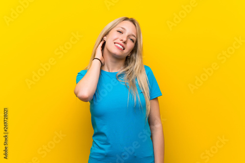 Young blonde woman over isolated yellow background having doubts