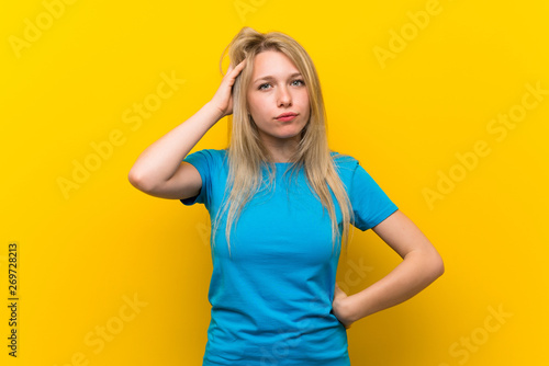 Young blonde woman over isolated yellow background with an expression of frustration and not understanding