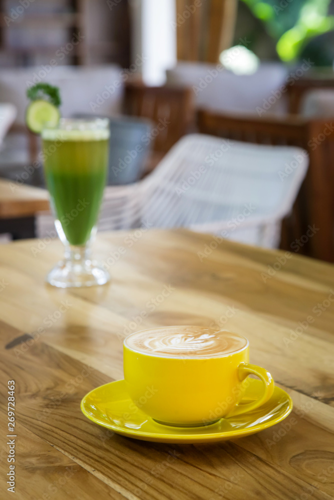 A cup of coffee and green detox drink served on the restaurant table