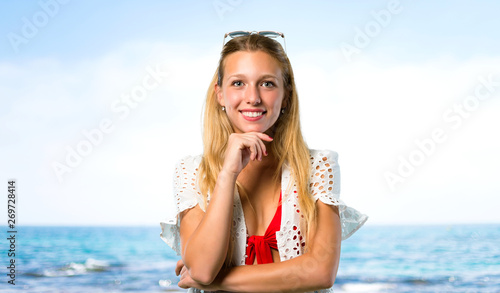 Blonde girl in summer vacation smiling and looking to the front with confident face at the beach © luismolinero