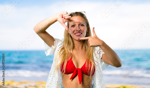 Blonde girl in summer vacation focusing face. Framing symbol at the beach