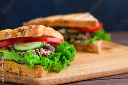 sandwiches with grilled bread tuna lettuce tomato cucumber on wooden cutting board 