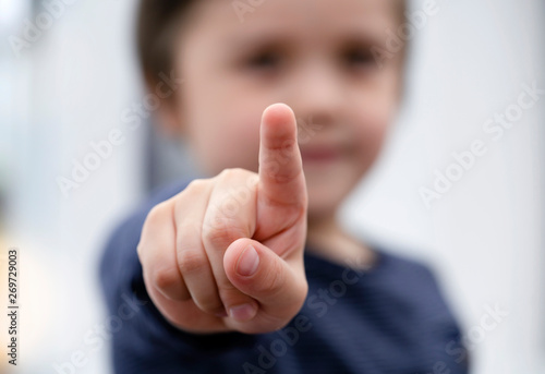 Blurry face of little boy finger pointing at camera, Selective focus of kid primary school boy pointing to you with his finger, Spoild children concept