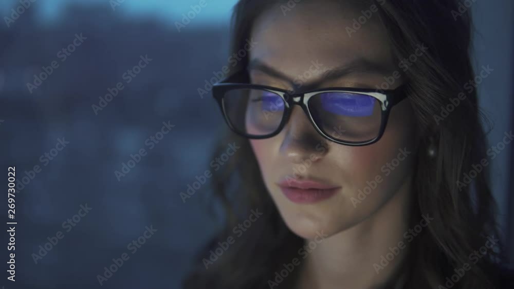 reflection of the monitor with glasses. attractive young girl working on a laptop reflection of the monitor with glasses. attractive young girl working on a laptop