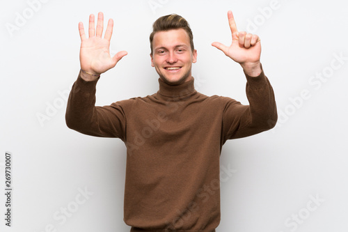 Blonde man over isolated white wall counting seven with fingers