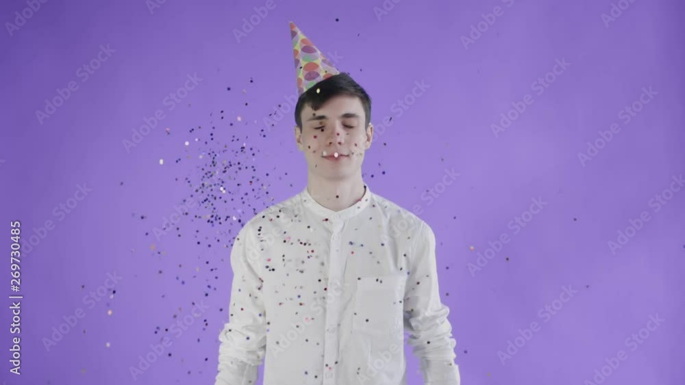 Confetti was thrown at the young man on a purple background. Slow motion Confetti was thrown at the young man on a purple background. Slow motion