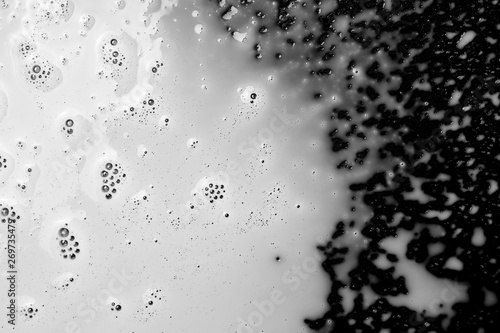 Spilled milk puddle with droplets isolated on black background and texture, top view