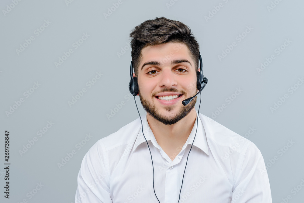 Handsome middle eastern man working with headset answering business calls as tech support dispatcher isolated over grey background - obrazy, fototapety, plakaty 