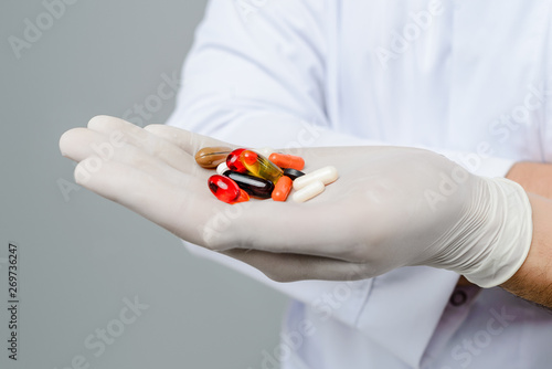 Hand of a medical doctor full of medicinal pills for health on grey background