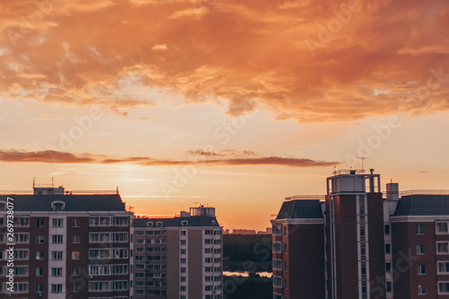 Orange-red sunset with clouds in summer with residential buildings