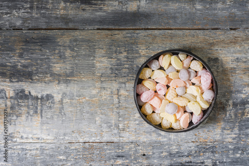 Colorful candies in a metal jar on a gray wooden background