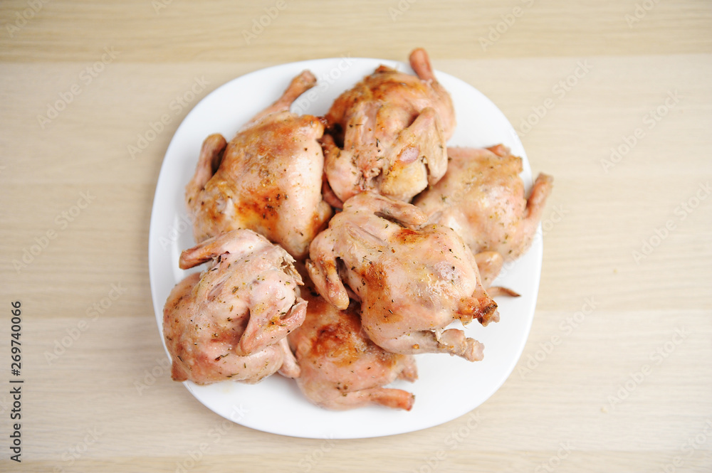 Six baked cornish hens on white plate top view Six baked cornish hens on white plate top view