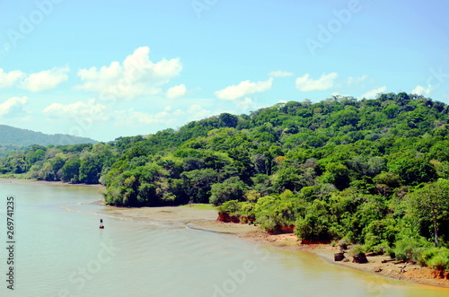 Green landscape of the Panama Canal, view from the transiting container ship.