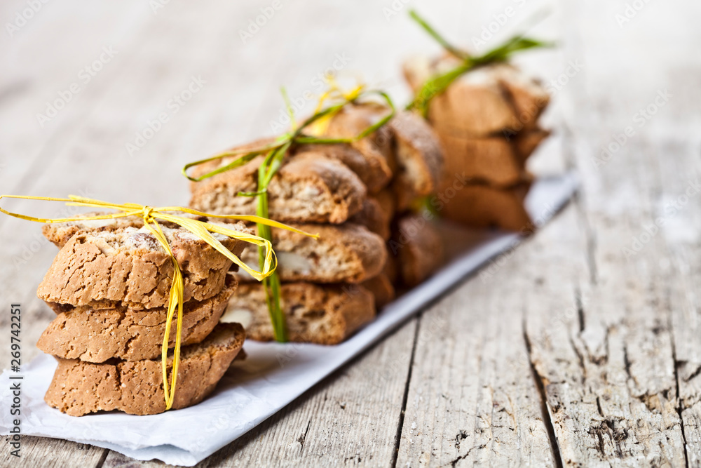 Fresh Italian cookies cantuccini with almond seeds stacks on white paper on ructic wooden table background. Fresh Italian cookies cantuccini with almond seeds stacks on white paper on ructic wooden table background.