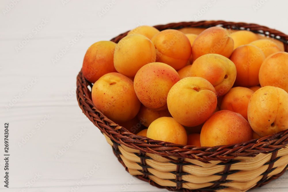 Ripe apricots are located in a wicker basket on a white background Ripe apricots are located in a wicker basket on a white background