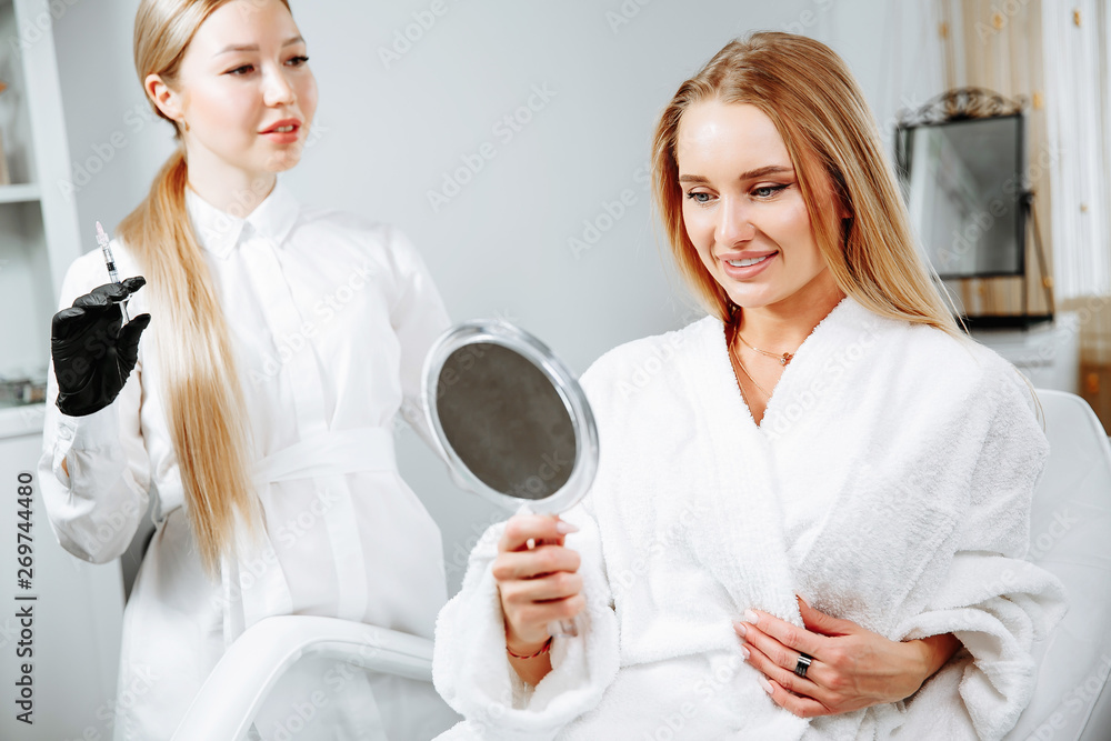 Fototapeta premium female client received cosmetic face treatments in clinic of aesthetic medicine, looking in mirror at results