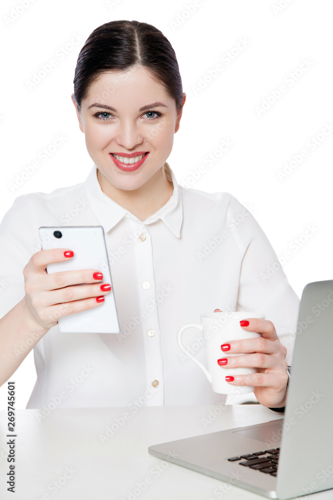 Portrait of happy successful attractive brunette businesswoman in white shirt sitting, holding cup of drink, smartphone and looking with toothy smile. indoor studio shot, isolated in white background. Portrait of happy successful attractive brunette businesswoman in white shirt sitting, holding cup of drink, smartphone and looking with toothy smile. indoor studio shot, isolated in white background.