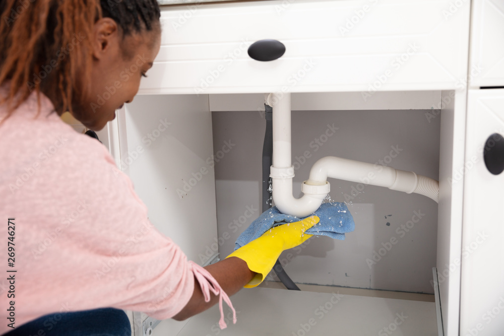 Woman Using Towel Under Leaking Sink Pipe Woman Using Towel Under Leaking Sink Pipe