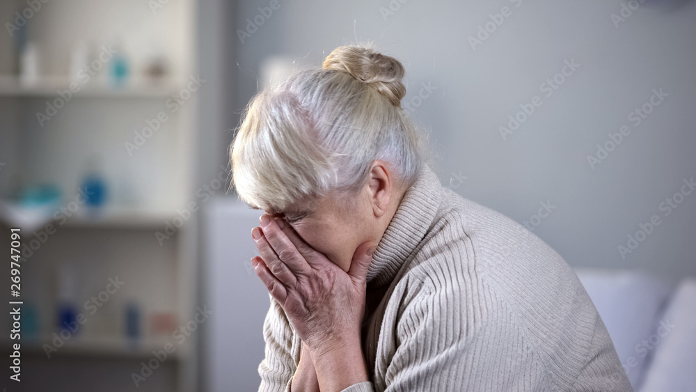 Unhappy elderly lady sitting alone in living room and deeply crying, depression Unhappy elderly lady sitting alone in living room and deeply crying, depression