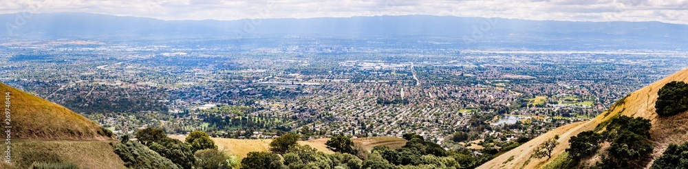 Panoramic view of San Jose, part of Silicon Valley; golden hills and residential areas visible in the foreground; the downtown area visible in the background; South San Francisco bay area, California