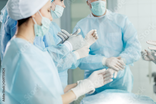 surgical hardworking team putting on latex gloves before performing surgery clinic. close up photo.