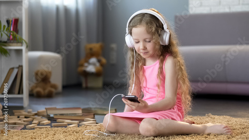 Girl in headphones using smartphone, learning pronunciation of foreign language