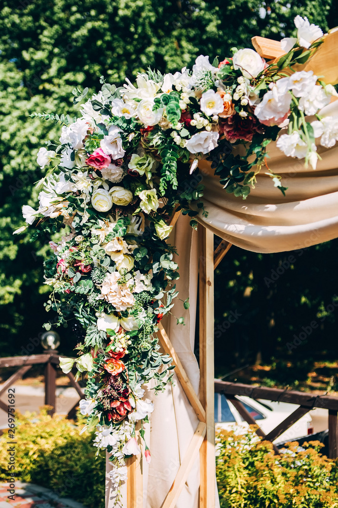 wedding ceremony in nature. the arch is covered with a beige fabric. wooden box for wedding rings.