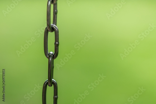 Close up of metal chain with blurred green nature lawn background.