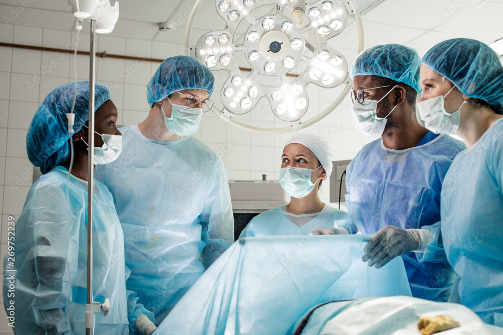 happy cheerful diverse doctors standing around the partient's bed and enjoying time. happy cheerful diverse doctors standing around the partient's bed and enjoying time.