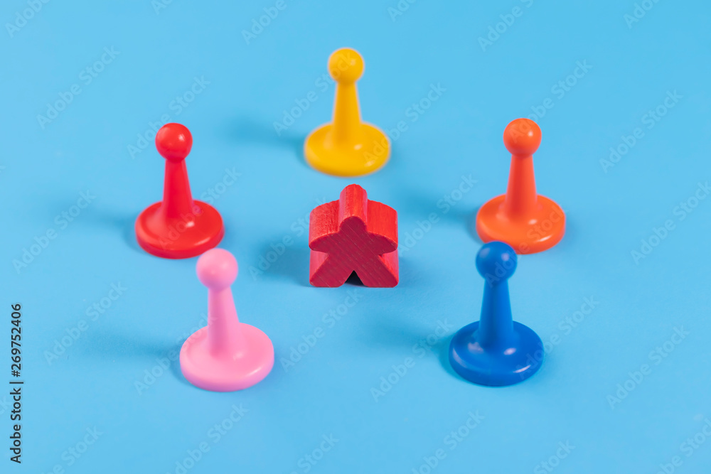 The wooden red figure is surrounded by several plastic multicolored The wooden red figure is surrounded by several plastic multicolored