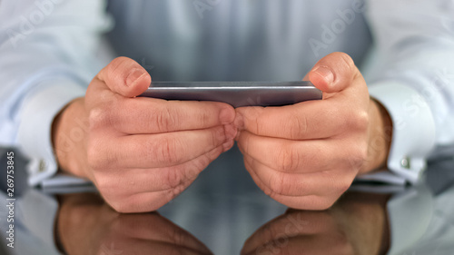 Office worker holding smartphone closeup, watching film online video application