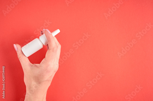 Nasal spray bottle composition with hand, white template bottle on pink background