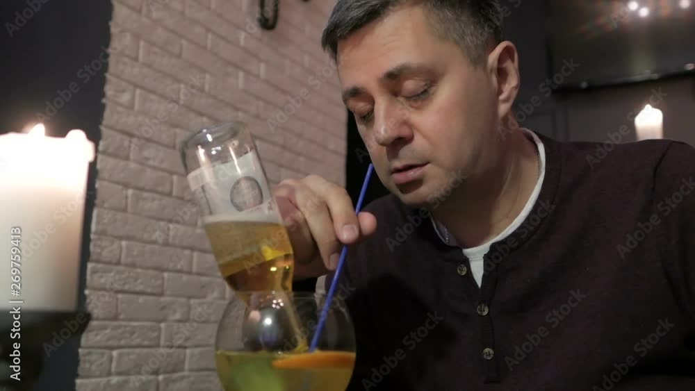 Drunk man continues to drink a cocktail. Loneliness and booze. Bachelor Drunk man continues to drink a cocktail. Loneliness and booze. Bachelor
