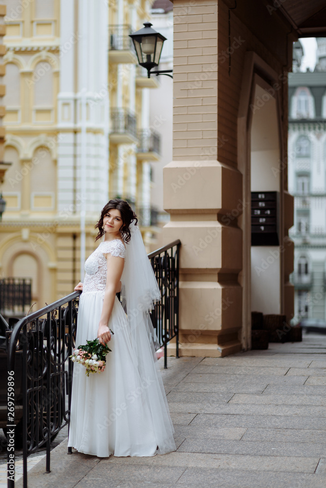 Caucasian happy young bride with wedding bouquet looks at camera and smiling