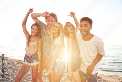 Group of happy friends having fun at ocean beach at dawn