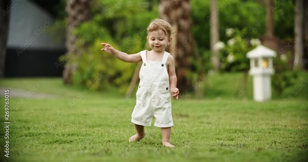 Cute emotinal baby running on grass in garden. Little adorable kit happily smiling and laughing - happy childhood concept 4k Cute emotinal baby running on grass in garden. Little adorable kit happily smiling and laughing - happy childhood concept 4k
