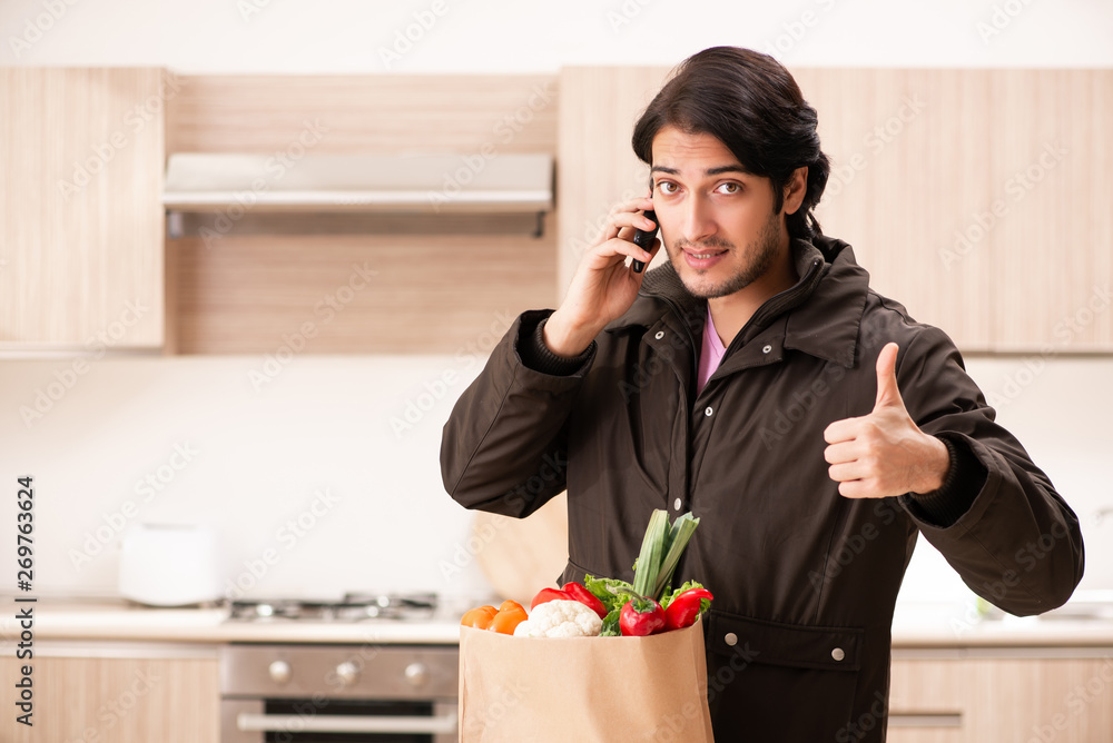 Young handsome man with vegetables in the kitchen 