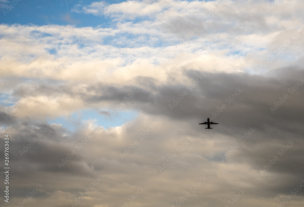 Passenger jet airplane on the background of the cloudy sky. Spring evening, overcast. Airplanes take off from the airport nearby.