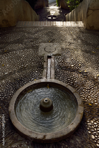 Fountain at the top of the water stairway at Generalife summer palace with white and black pebble walkway Granada photo