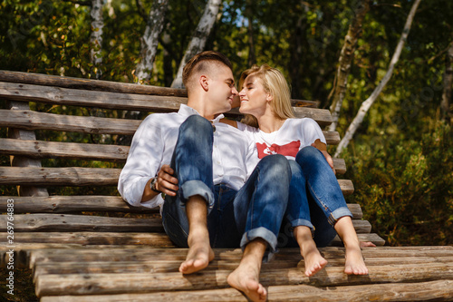 happy couple in love sitting on a bench in the forest in summer